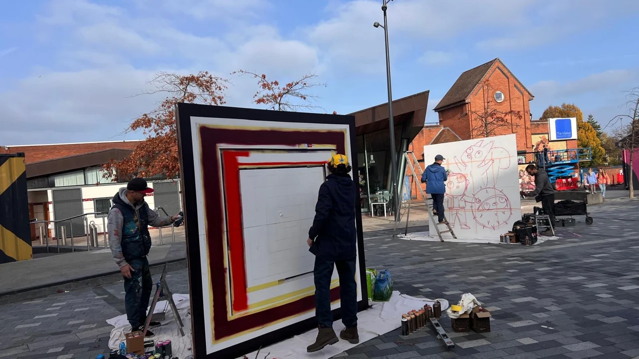 People painting freestanding panels in Lyceum Square, with ladders and paint supplies nearby.