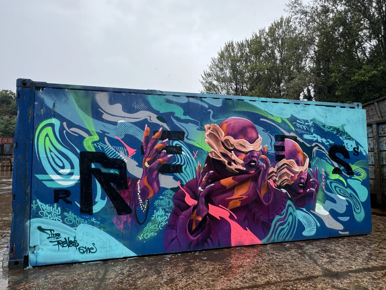 A turquoise trailer painted with vivid interlocking figures and lettering.