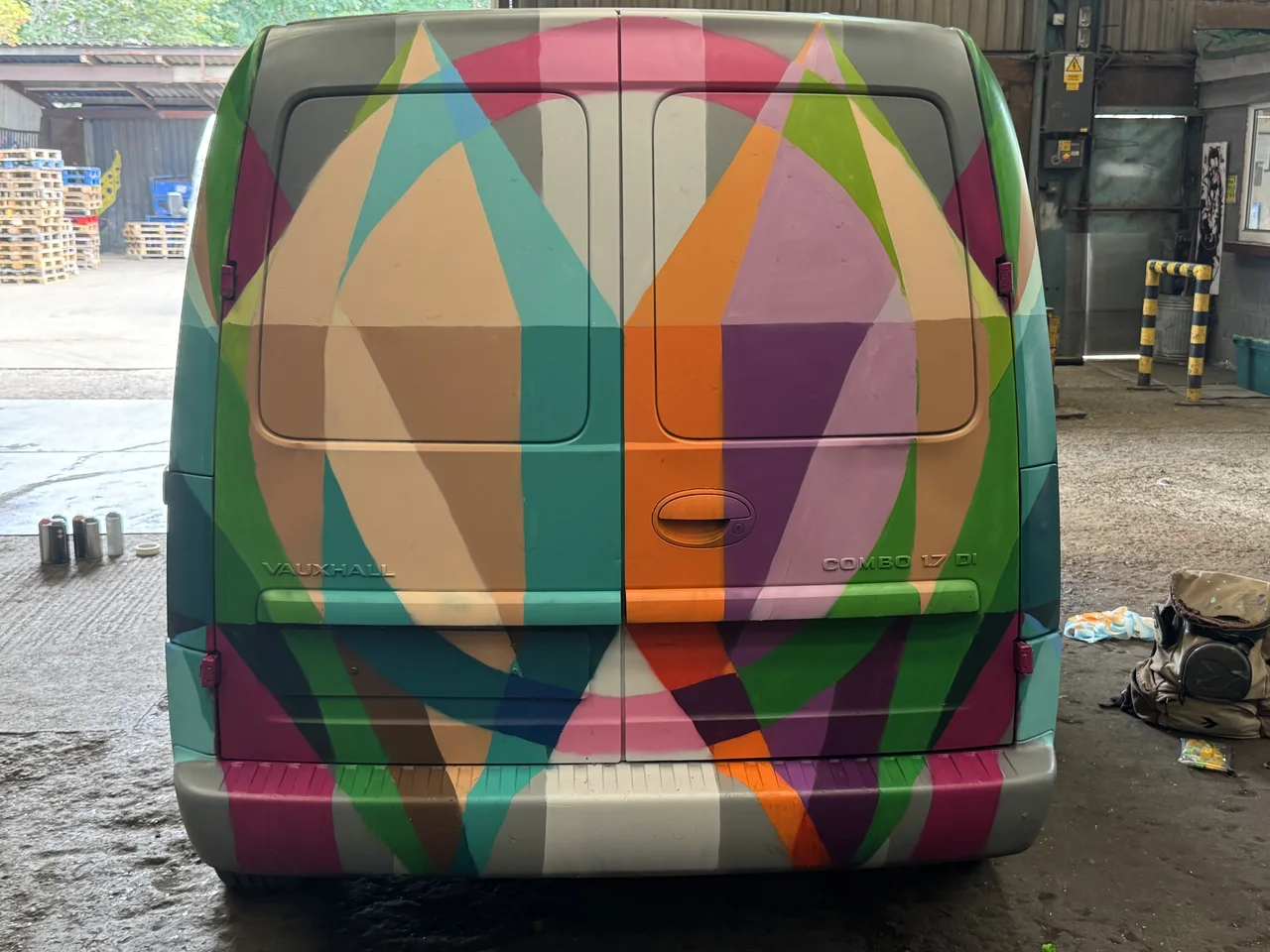The rear of a van covered in overlapping colourful geometric shapes.
