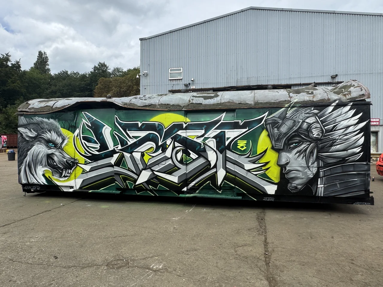 A trailer painted with lime-green and monochrome lettering and a bird-like figure.