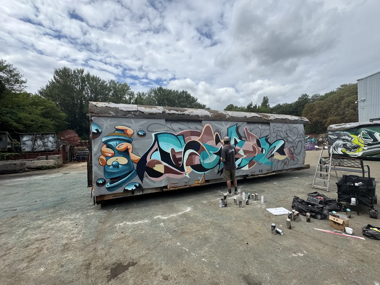 A long scrapyard trailer covered in blue, orange and white graffiti.