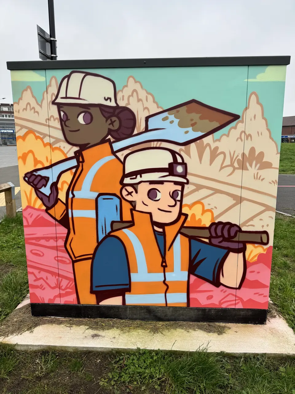 Painted utility cabinet: two illustrated track workers in hard hats and orange hi-vis carry a shovel and a tool over pink and amber landscape.