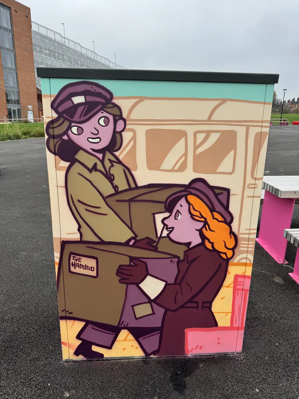 Painted utility cabinet: two illustrated women in uniform carry a large parcel past a railway carriage. A parcel label reads 'The Hammo'.
