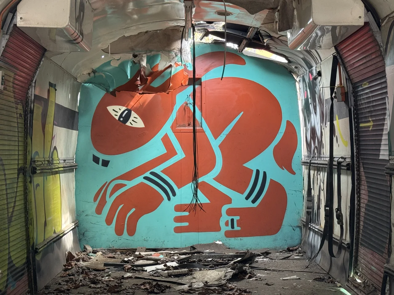 An orange graphic character painted on turquoise inside a stripped vehicle.