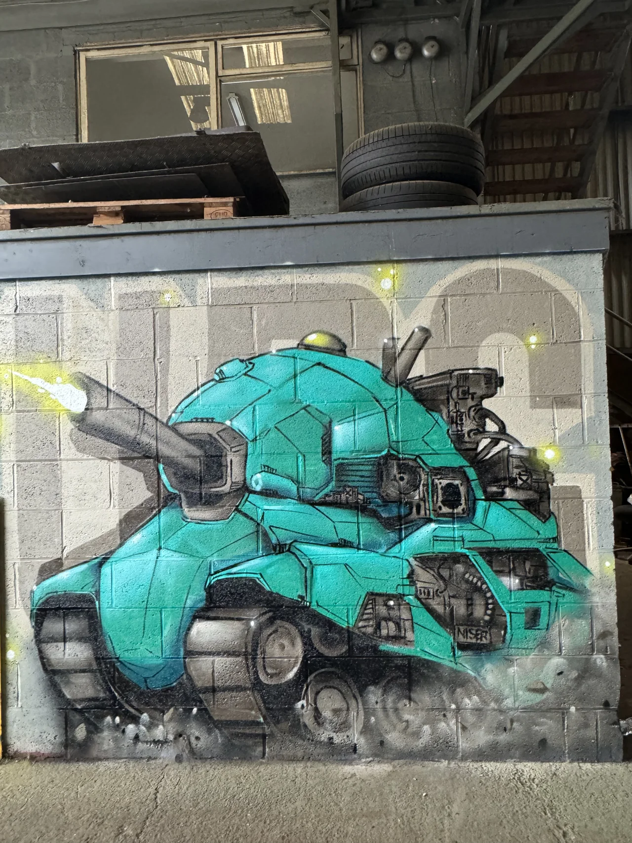 A turquoise mechanical character painted on a workshop panel.