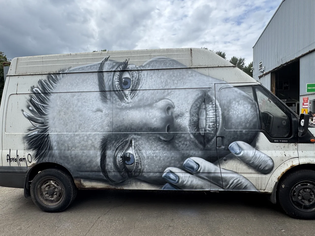 A monochrome portrait painted across the side of a white van.