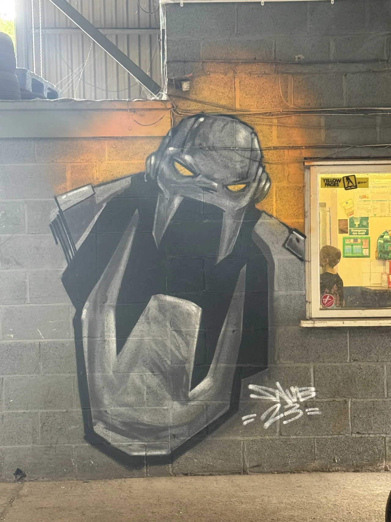A large dark mechanical character painted on a workshop panel.
