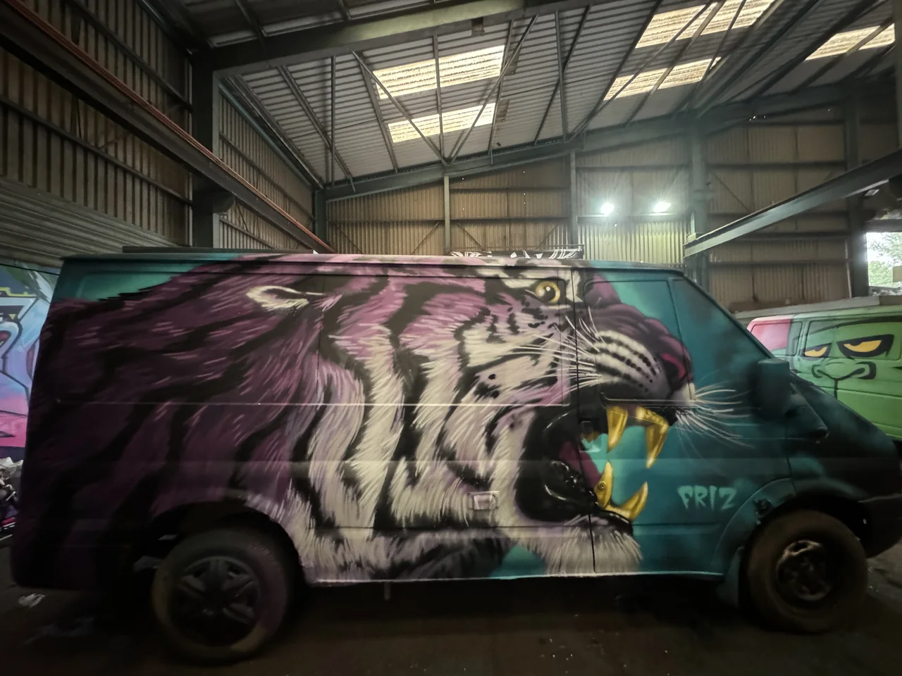 A van painted with a roaring tiger inside the workshop.