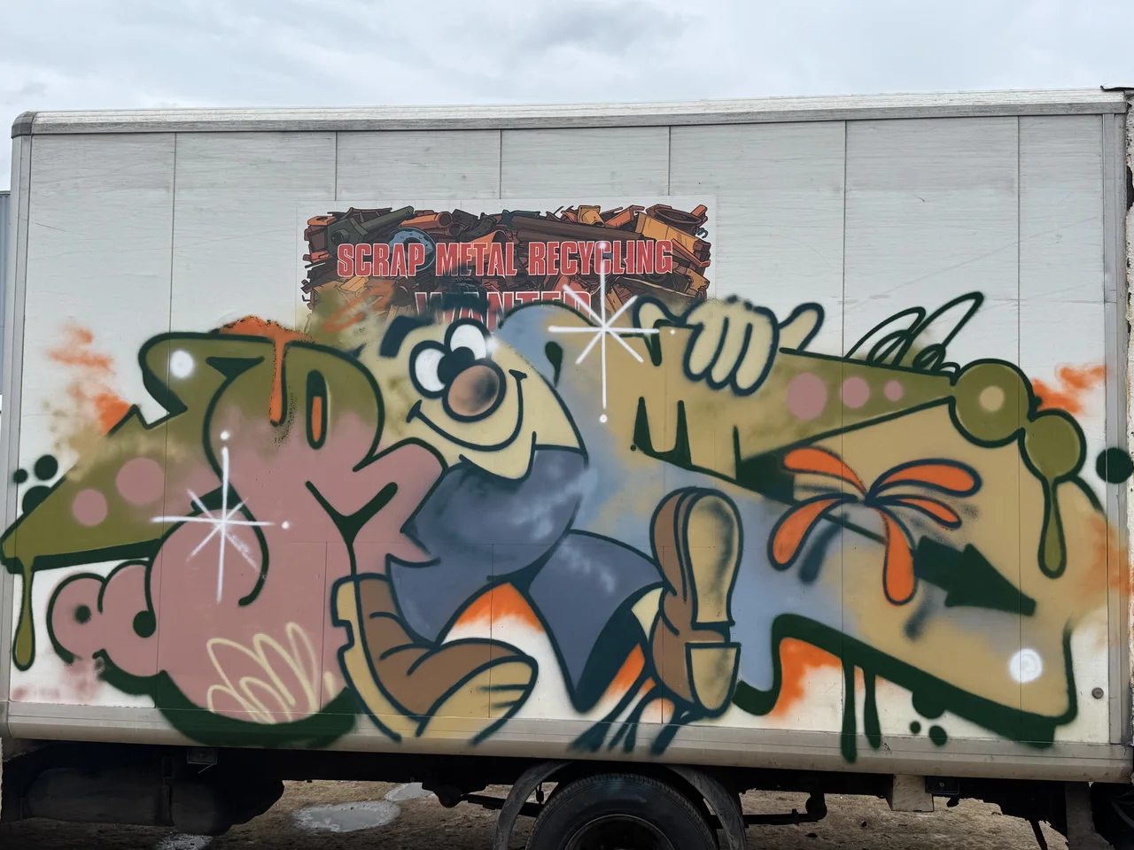 A white van covered in flowing green, pink and yellow graffiti.