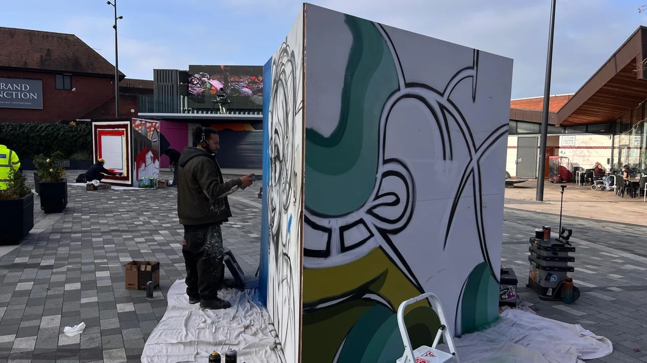 Curving outlined lettering and green shapes on a freestanding panel in Lyceum Square.