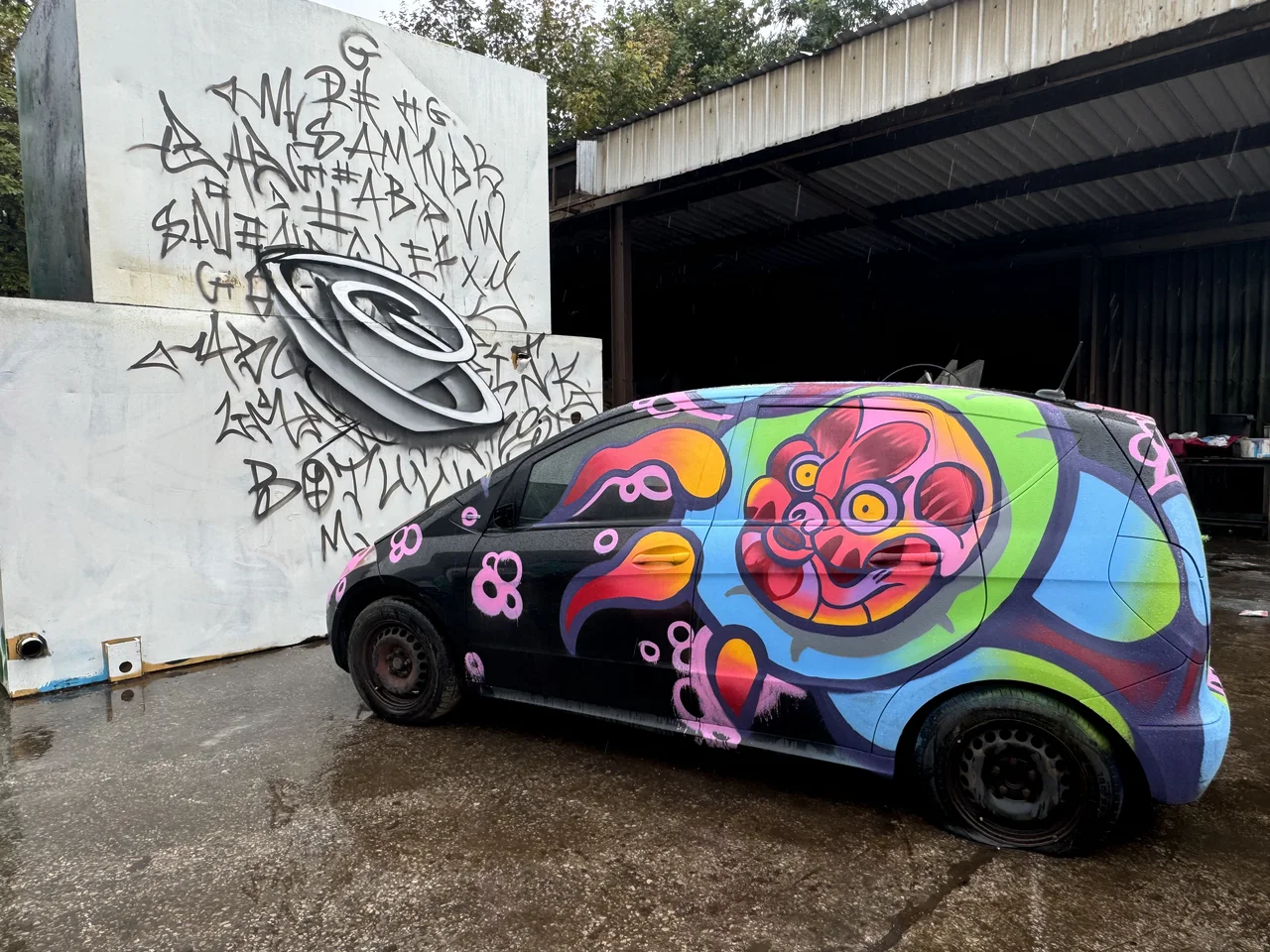 A small car painted with a bright pink and orange circular floral design.