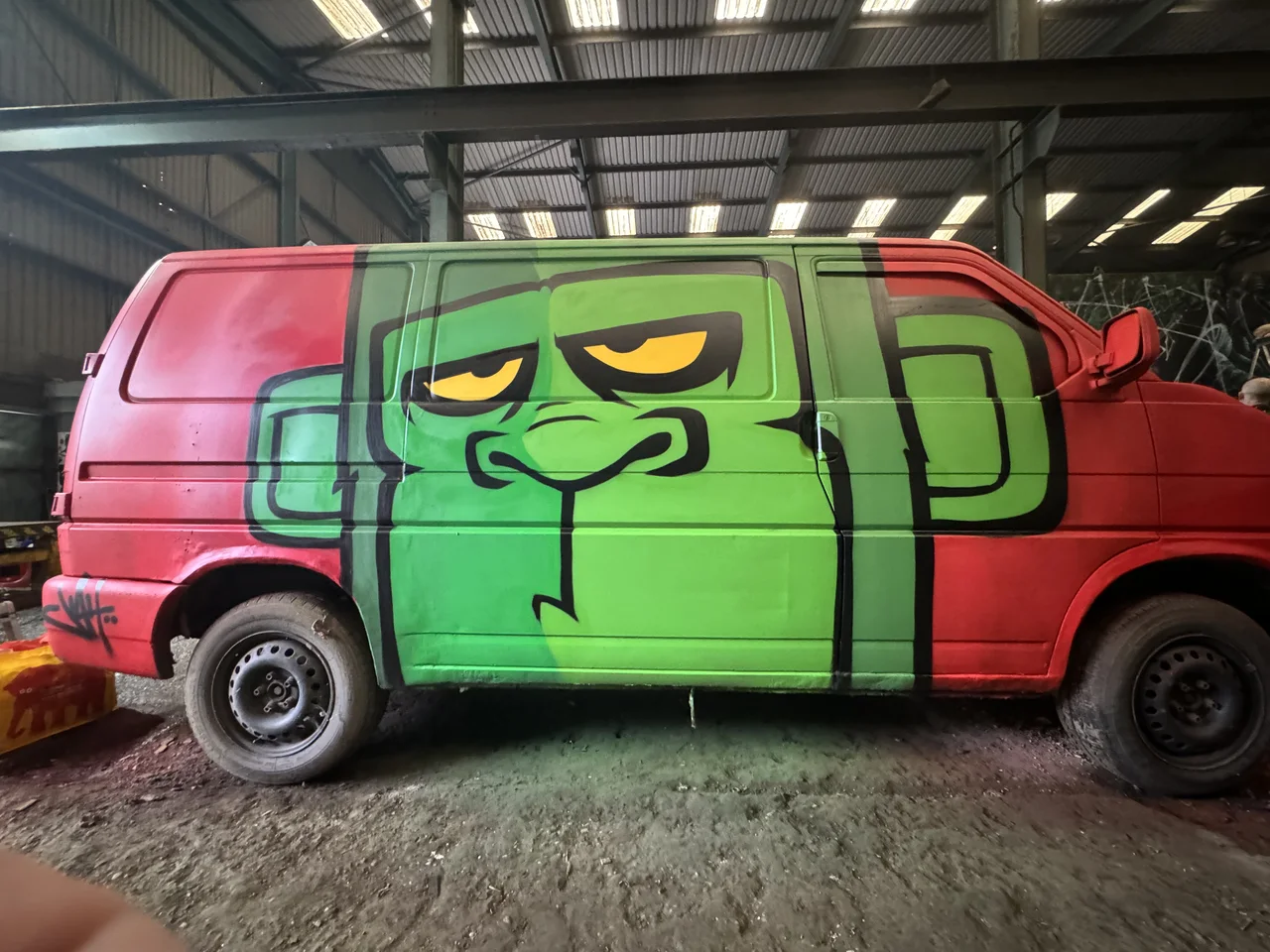 A red van with a large green cartoon face painted across its side.