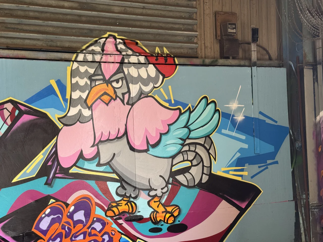 A pink and grey cartoon bird painted over a colourful geometric background.
