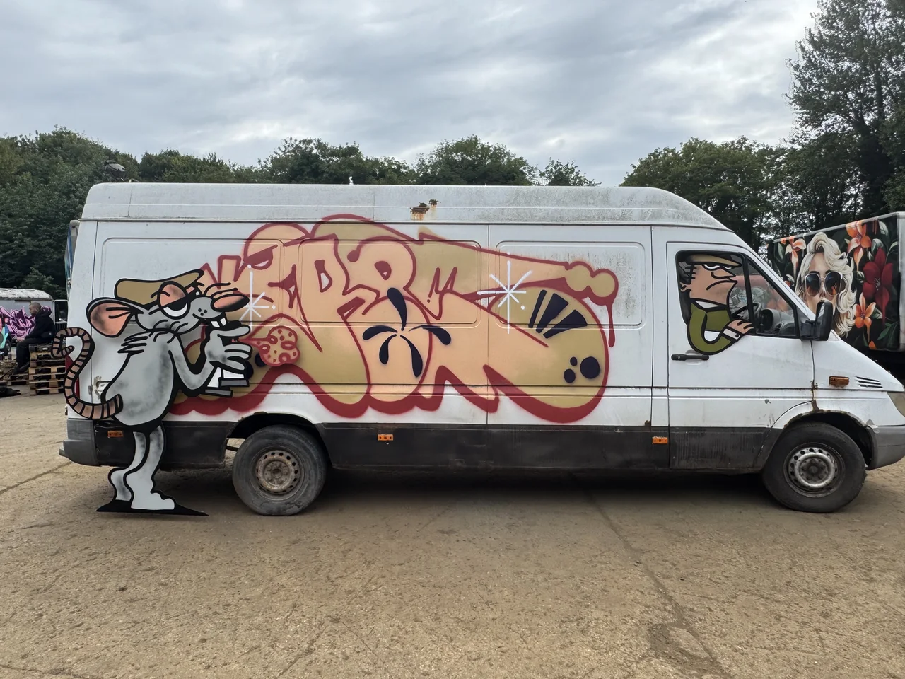 A white van painted with rounded pink and brown graffiti lettering.