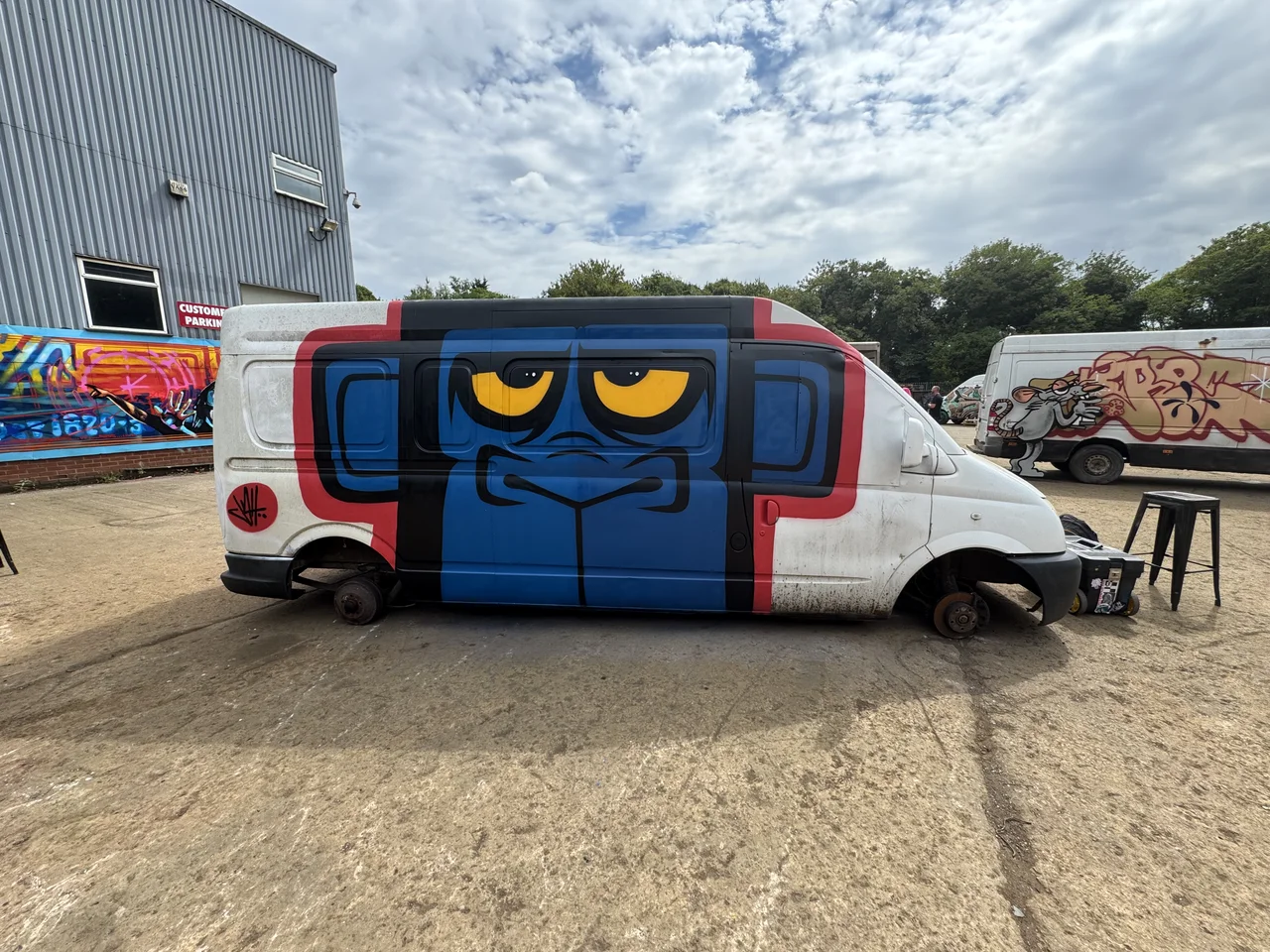 A white van with a blue cartoon face painted across its side.