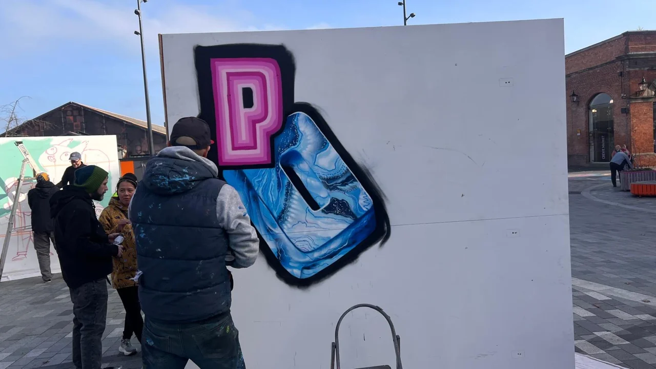 People beside a freestanding panel with bold blue and pink lettering in Lyceum Square.