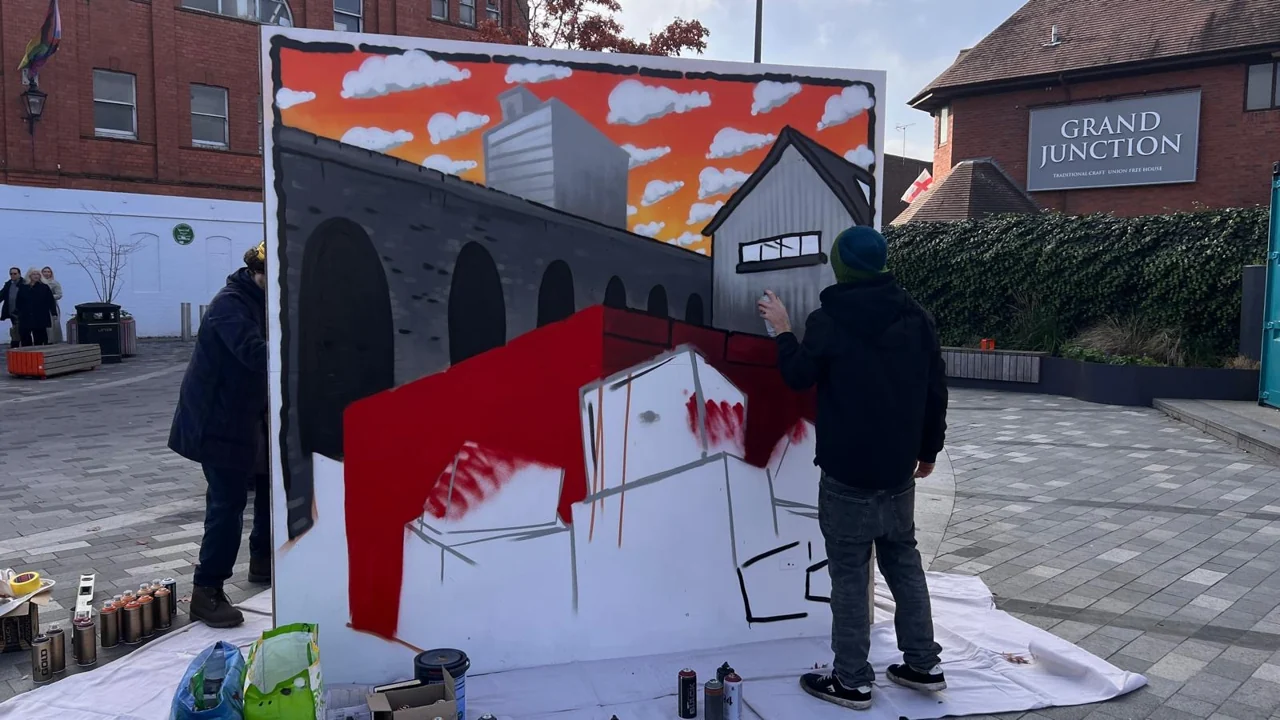 People painting a red, white and grey architectural scene on a panel in Lyceum Square.