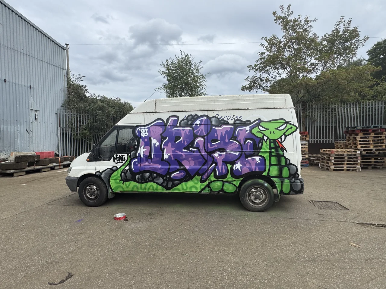 A white van with rounded purple graffiti lettering and green highlights.